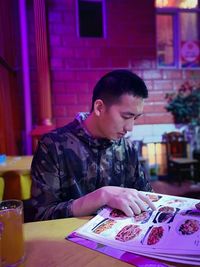 Young man looking down while sitting on table