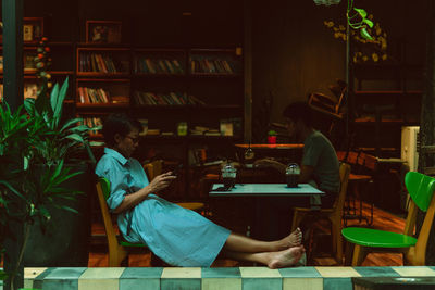 Rear view of woman sitting on table