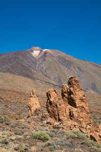 Scenic view of rocky mountains against clear blue sky