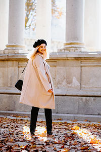 Woman looking away while standing by autumn leaves