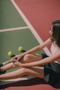 High angle view of smiling woman with racket sitting at tennis court