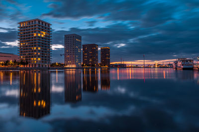 Reflection of illuminated buildings in city at sunset