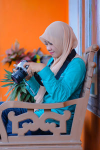 Side view of young woman using mobile phone while sitting on table