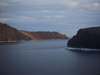 Scenic view of sea and mountains against sky