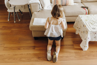 Rear view of woman sitting on hardwood floor