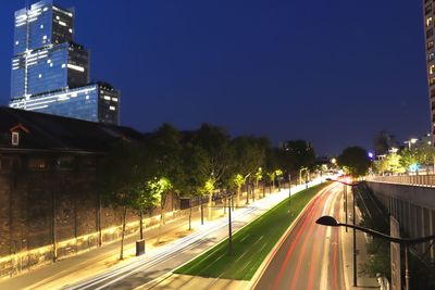 Light trails on road in city against sky at night