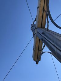 Low angle view of telephone pole against clear blue sky