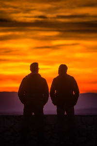 Silhouette man standing by sea against sky during sunset