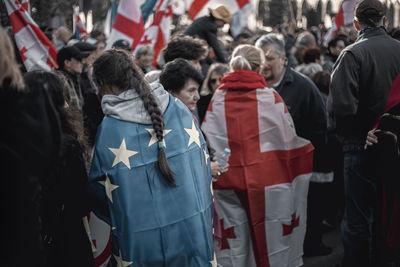 Crowd with flags protesting on street in city