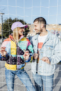 Girlfriend and boyfriend clutching the fence looking each other. happy couple.