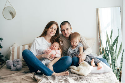 Family portrait of mom and dad with little kids.