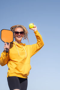 Portrait of young woman holding globe against blue background