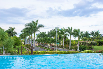 Swimming pool by trees against sky