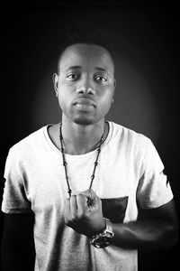 Portrait of young man standing against black background