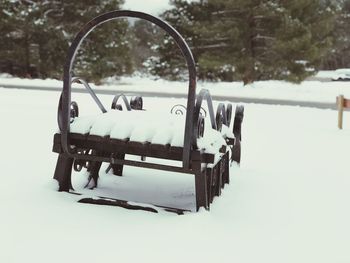 Close-up of empty bench on snow covered field