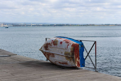 Abandoned boat moored at beach against sky