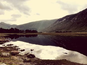 Scenic view of lake by mountains against sky