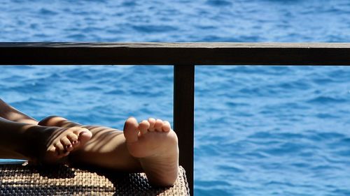 Low section of girl relaxing by sea