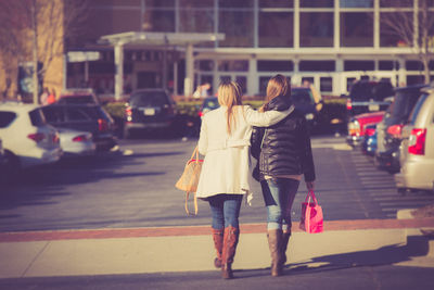 Rear view of female friends walking on city street