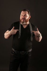 Portrait of mature man standing against black background