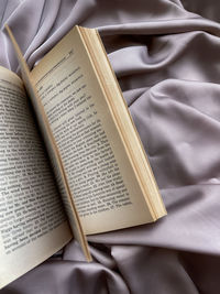 High angle view of open book on bed