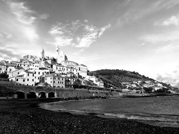 View of buildings by sea against sky in city