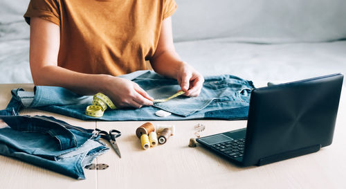 Midsection of man using mobile phone while sitting on table