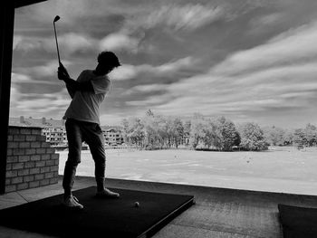 Full length of man playing golf against cloudy sky