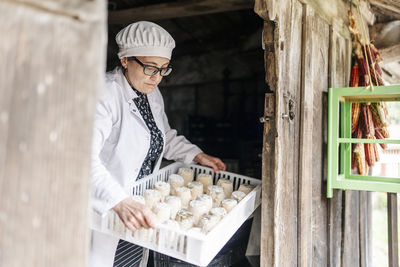 Female owner holding cheese tray at doorway