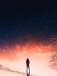 Reflection of sky and person in lake during sunset