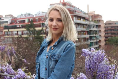 Portrait of young woman with flowers in background