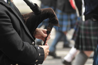 Midsection of street musician playing bagpipe