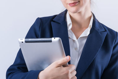 Midsection of woman using smart phone against white background