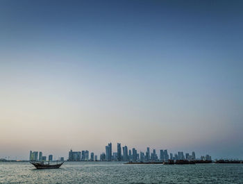 Sea by buildings against clear sky