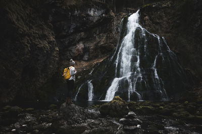 Woman standing on rock by waterfall