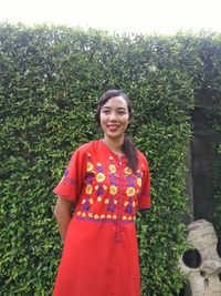 Portrait of smiling young woman standing against plants