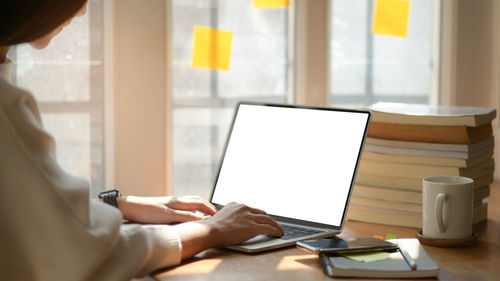 Midsection of woman using laptop on table
