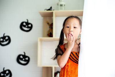 Closeup portrait little girl with surprised face in holloween costume in room in halloween festival