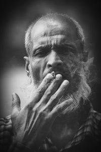 Close-up portrait of mature bearded man smoking cigarette 