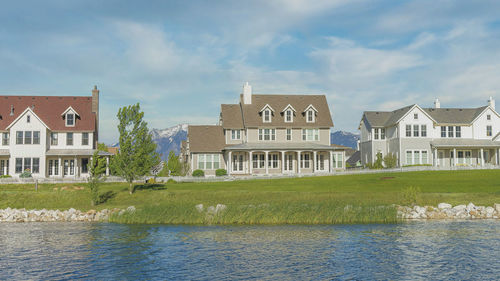 Houses by river against sky