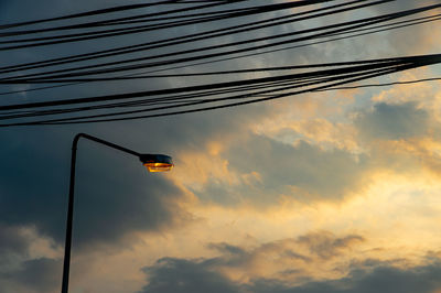 Low angle view of power lines against sky at sunset