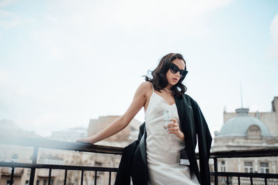 Woman standing by railing against sky