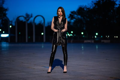 Portrait of woman standing against illuminated city at night