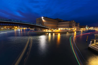 Illuminated bridge over river against sky at night