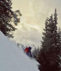 Person skiing on snowcapped mountain against cloudy sky during sunset
