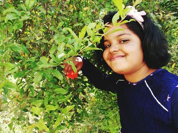 Close-up portrait of smiling woman with apple on tree