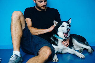 Man with dog sitting against blue wall