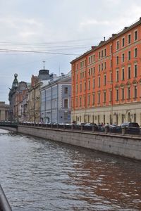 Buildings by river against sky in city