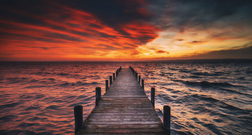 Pier over sea against sky during sunset