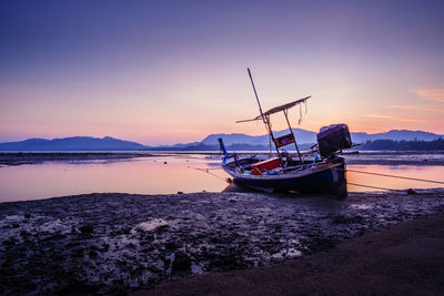 Scenic view of sea with boat moored at beach against sky during sunset